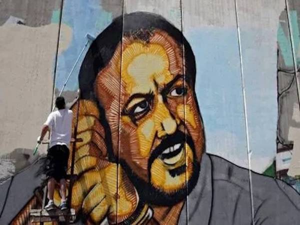 Gambar fail menunjukkan seorang pelukis menyiapkan lukisan potret pemimpin kanan Fatah, Marwan Barghouti di tembok sempadan dekat pusat pemeriksaan yang dikawal Israel antara Baitulmuqaddis dengan Ramallah, Palestin. - Foto AFP