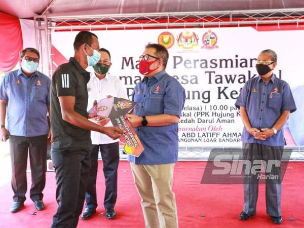 Abd Latiff (dua dari kanan) menyampaikan replika kunci kepada salah seorang penerima ketika majlis perasmian Projek Taman Desa Tawakkal PPK Hujung Keton pada Selasa.