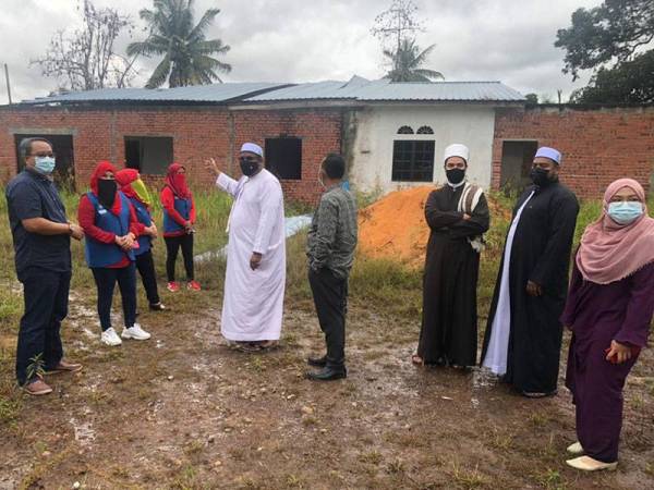 Muhamad Hisham (tengah) menunjukkan kompleks madrasah yang sedang dalam pembinaan di Kampung Parit Talibek, Simpang Renggam.