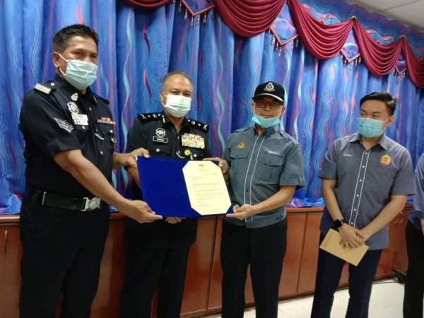 Mat Shah (kiri) menerima sijil penghargaan Menteri Dalam Negeri yang disampaikan oleh Zulkifli (tiga kiri) sambil diperhatikan Che Zakaria (dua kiri).