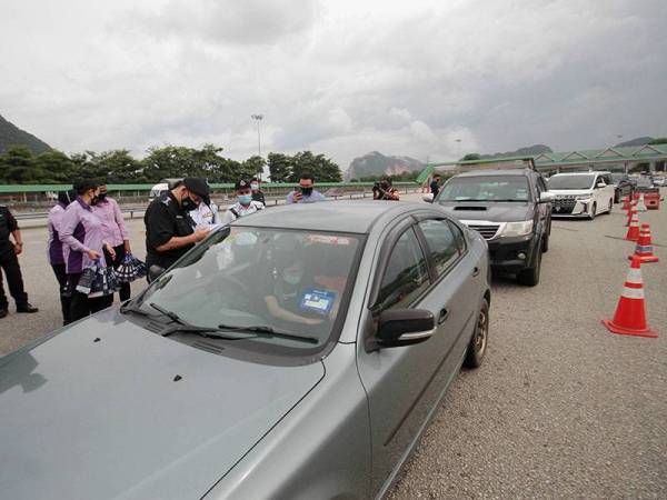Ketua Polis Perak Datuk Mior Faridalathrash Wahid memeriksa maklumat pemandu kenderaan bagi memantau prosedur operasi standard (SOP) yang ditetapkan oleh kerajaan ketika lawatan kerja di Sekatan Jalan Raya (SJR) Tol Ipoh Selatan (Arah Utara) hari ini.