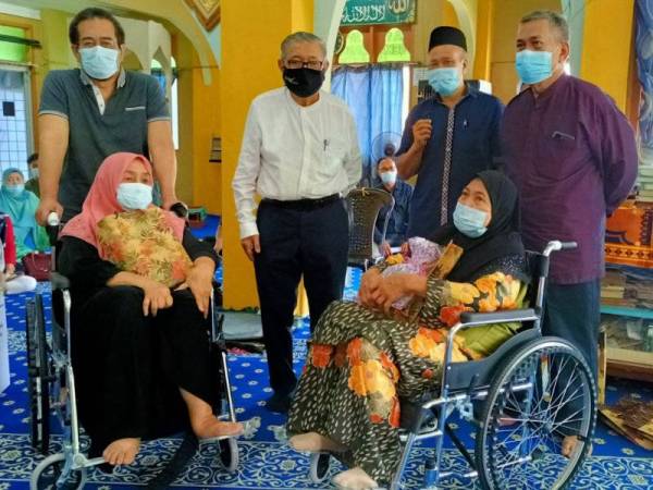 Mangsa dari zon kuning iaitu Wan Noraini Wan Ahmad, 76, (kanan) dan Zainab Harun, 72, (kiri) turut sama menerima sumbangan berbentuk kerusi roda yang disampaikan oleh Zaman Khan (tiga dari kanan).