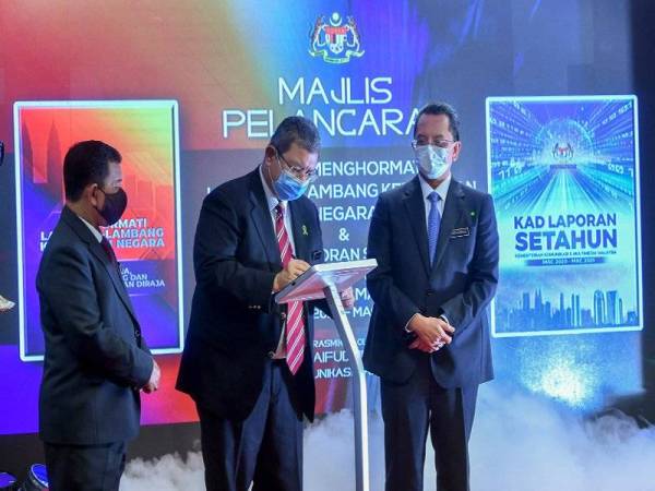 Saifuddin (tengah) melancarkan Buku Menghormati Lambang-lambang Kebesaran Negara dan Kad Laporan Setahun KKMM di Putrajaya pada Selasa. Foto Bernama