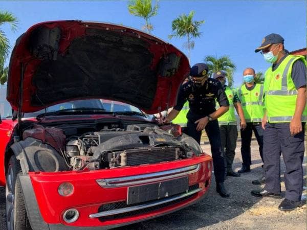 Hanif Yusabra (kiri) memeriksa nombor casis di salah sebuah kenderaan yang disita.