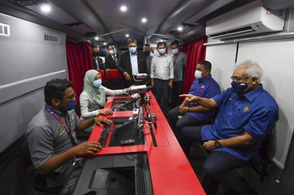 Hamzah melihat proses pendaftaran MyKad di dalam Bas Mobile Jabatan Pendaftaran Negara (JPN) Generasi Baharu yang dilengkapi kemudahan sistem percetakan MyKad di pekarangan JPN hari ini. -Foto Bernama