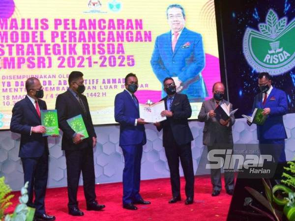 Pengerusi RISDA, Datuk Mohd Salim Sharif (tiga dari kiri) memberikan buku Model Perancangan Strategik (MPSR) 2021-2025 kepada Abdul Latiff (tiga dari kanan) pada Khamis.