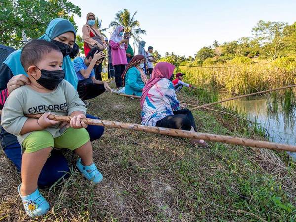 Nur Alya Izzati Mazlan, 20, bersama sepupunya Ammar Fayyadh antara peserta yang mengambil bahagian pada pertandingan memancing secara tradisional di tali air sawah kampung Bukit Kechik, Melor di sini.