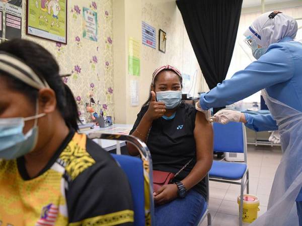 Pasukan sukarelawan Jabatan Kemajuan Orang Asli Pahang Norsimawati Mat, 23, (dua, kiri) menerima suntikan vaksin Covid-19 jenis Pfizer BioNTech di Pusat Kesihatan Daerah (PKD) Jerantut, hari ini.