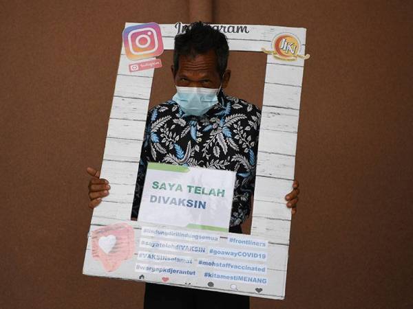 Tok Batin Kampung Orang Asli Sungai Enggang Geng Nyai, 56, bergambar bersama replika Instagram selepas menerima suntikan vaksin Covid-19 jenis Pfizer BioNTech di Pusat Kesihatan Daerah (PKD) Jerantut, hari ini.