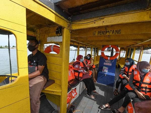 Wan Mohd Alif (kiri) membawa penumpang dari Pasar Besar Kedai Payang ke jeti Seberang Takir. - Foto Bernama