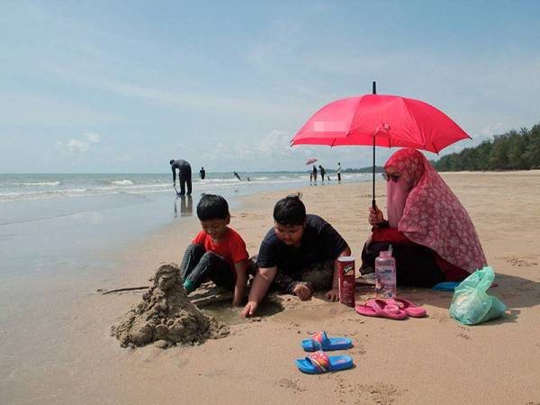 Murni Amin, 34, berpayung berikutan cuaca panas semasa menemani anaknya Aimuni Aiman, 8, (tengah) dan Naqib Aiman, 7, (kiri) berkelah di Pantai Kempadang hari ini.