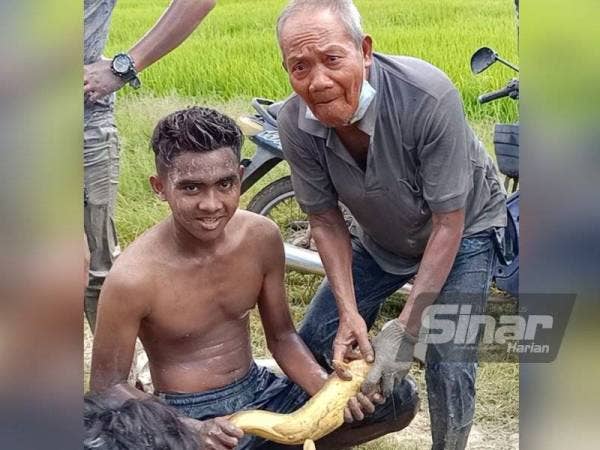 Mohd Alif Azwan (kiri) menunjukkan ikan haruan yang berjaya ditangkapnya.