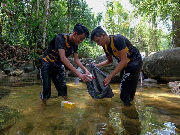 Pengunjung, Mohamad Shahmirul Aswad Sabaruddin, 24, (kanan) bersama adiknya Muhammad Dahmin Izmar Aqif Sabaruddin, 18, (kiri) mengutip sampah sarap yang hanyut di air terjun sempena Hari Air Sedunia, di Air Terjun Taman Eko Rimba Kledang Saiong hari ini.