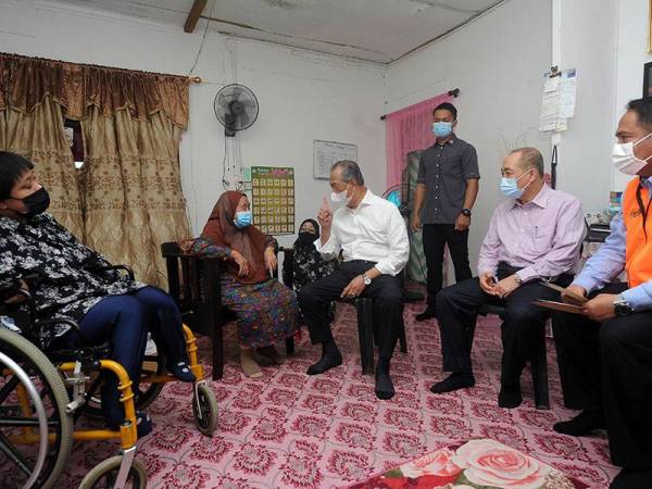 Perdana Menteri Tan Sri Muhyiddin Yassin (duduk, empat, kanan) menyantuni Dayang Amit Budin, 82, (dua, kiri) sewaktu mengadakan ziarah prihatin di rumah warga emas itu di Kampung Sembulan Tengah, hari ini. 