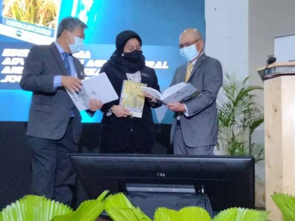 Ronald Kiandee (kanan) membaca salah sebuah buku berkaitan kejuruteraan pertanian yang dilancarkan pada majlis perasmian NAFEC 2021 di Ibu Pejabat MARDI di Serdang pada Selasa.