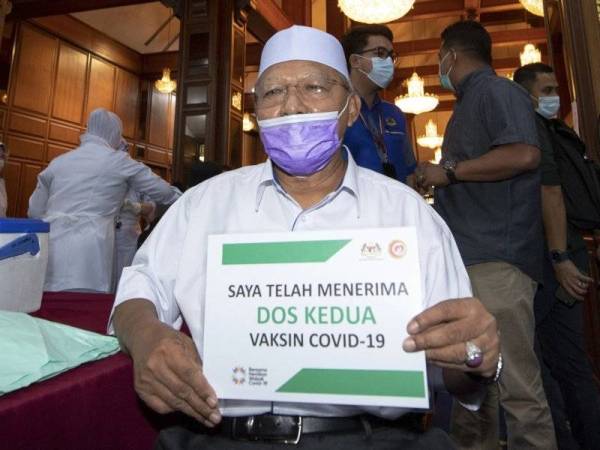 Ahmad menunjukkan plakad 'Saya telah menerima dos kedua vaksin Covid-19' di Dewan Bunga Teratai Kompleks Kota Darulnaim pada Selasa. - Foto Bernama
