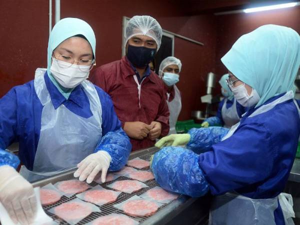 Haris (tengah) memantau para pekerja menghasilkan kepingan burger di kilang Arisprop Holdings di Gombak, Selangor.