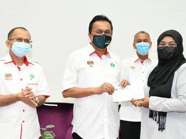 Mohd Salim (tiga, kanan) menyampaikan sumbangan kepada salah seorang penerima.