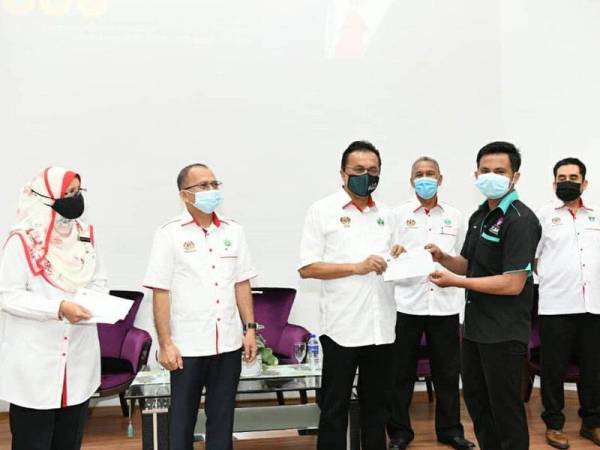 Mohd Salim (dua dari kanan) menyampaikan sumbangan kepada salah seorang pelajar.