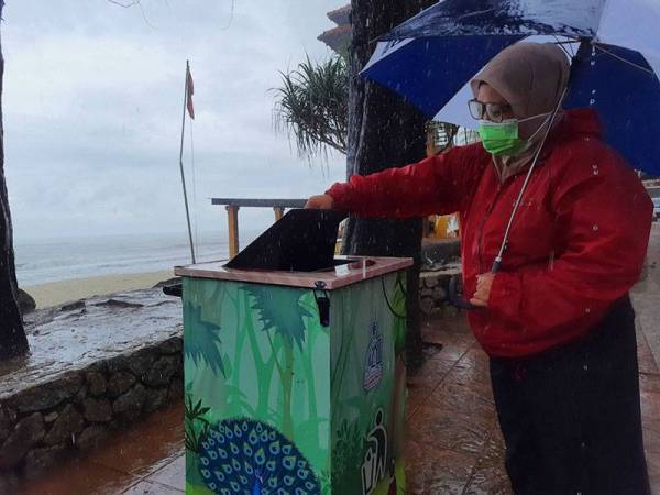 Seorang pengunjung membuang sisa makanan ke dalam tong sampah khas yang diletakkan di kawasan Teluk Cempedak.