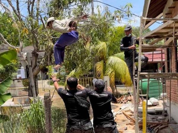 Aksi seorang pekerja asing yang bertindak terjun melintasi pagar dalam operasi dijalankan Jabatan Imigresen Malaysia Terengganu di Kampung Pulau Kudat, Hulu Terengganu.