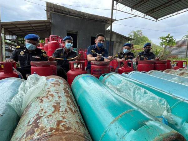 Mohd Ridzuan (tengah) bersama pegawainya menunjukkan gas LPG yang dirampas dalam serbuan pada awal pagi Rabu.