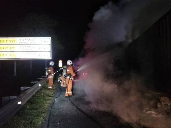Anggota bomba dan penyelamat sedang memadamkan kebakaran kenderaan di Kilometer 221 Lebuh Raya Utara Selatan (PLUS) arah selatan di sini, pagi Jumaat.