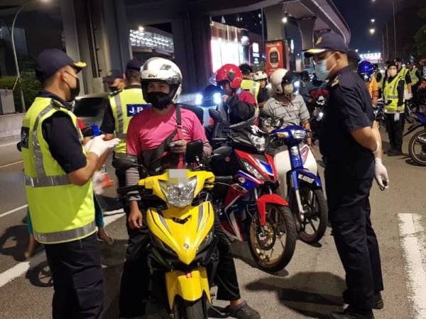 Mohd Zaki (kanan) melakukan pemeriksaan terhadap penunggang motosikal dalam Operasi Bersepadu di Jalan Cheras berhampiran Stesen MRT Taman Mutiara, Cheras, Kuala Lumpur pada Jumaat.