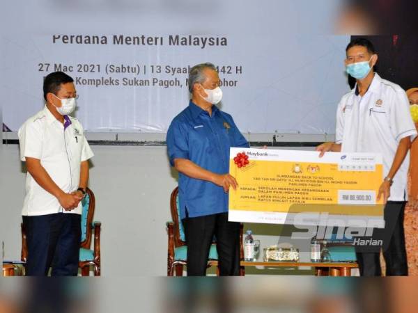 Muhyddin (tengah) menyerahkan sumbangan Back To School Parlimen Pagoh di Kompleks Sukan Pagoh pada Sabtu.