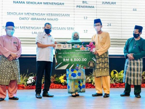 Che Zakaria (dua dari kiri) menyerahkan replika cek sumbangan ‘Back To School 2021’ KEJORA kepada Abd Taib di Dewan Kejora, Bandar Penawar.