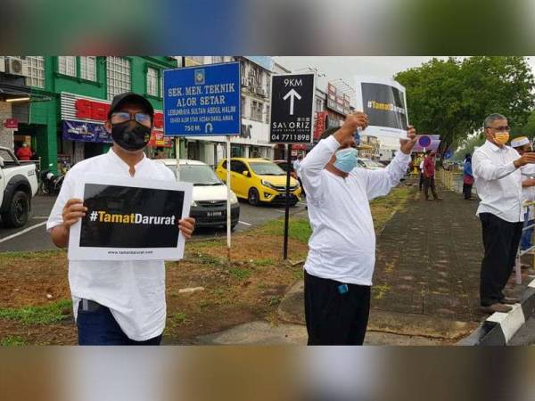 Mohd Asmirul (kiri) dan Ismail (kanan) ketika menyertai 'flash mob' di persimpangan Simpang Kuala sambil memegang sepanduk ‘Tamat Darurat’ dan melaungkan ‘Hidup Rakyat Tamat Darurat’.