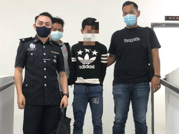 Tertuduh (tengah) dikawal polis ketika keluar dari bilik Mahkamah Sesyen Kota Bharu pada Selasa.