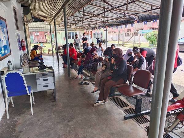 Syarifah Ramlee (duduk, paling hujung) bersama sebahagian ahli keluarganya di pekarangan Bilik Mayat Hospital Hulu Terengganu.