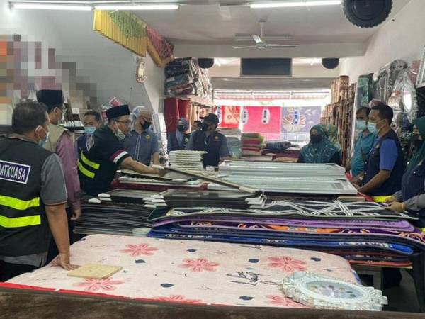 Penguat kuasa KDN memeriksa bingkai di sebuah premis.