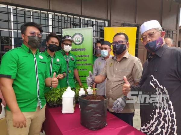 Zainol Fadzi (dua dari kanan) melakukan gimik menanam cili ketika merasmikan penutupan Kursus Fertigasi Cili @ Sungai Manik anjuran Pusat Aspirasi Anak Perak (Pasak) di Teluk Intan pada Khamis.