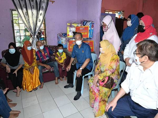 Muhyiddin (duduk, tiga dari kanan) dan isteri (duduk, dua dari kanan) melawat kediaman Selha (dua dari kiri) pada Program Ziarah Kasih di Kampung Sindang Baru, Kota Samarahan pada Jumaat. - Foto Bernama