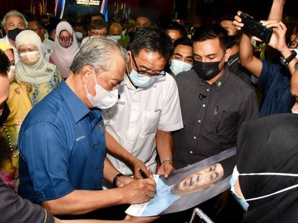 Muhyiddin (dua dari kiri) menandatangani potret beliau pada Program Perjumpaan Masyarakat Samarahan di Institut Pendidikan Guru Kampus Tun Abdul Razak (IPGKTAR) Kota Samarahan pada Jumaat. - Foto: Bernama