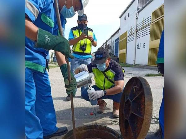 Anggota Bahagian Penguatkuasaan SPAN sedang memeriksa lubang kumbahan di lokasi serbuan.