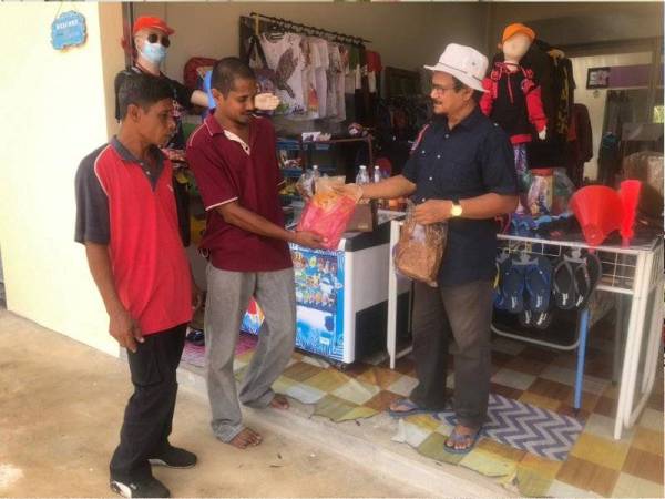 Peniaga, Roslan Abdul Rahman (kanan) menyantuni pengunjung yang berminat untuk membeli produk keluaran tempatan, serunding daging yang dijual olehnya di Plaza Indonesia-Malaysia-Thailand Golden Triangle (IMT-GT) Bukit Bunga, Tanah Merah.