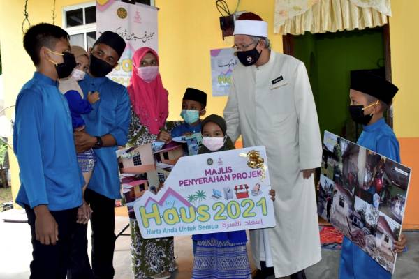Dr Zulkifli Mohamad Al-Bakri (dua, kanan) beramah mesra bersama salah seorang anak penerima bantuan MyHaus, Airiel Ashraf Azizi, 14, pada Majlis Penyerahan MyHaus 2021 Majlis Agama Islam Melaka (MAIM) di Batu 13, Kampung Asam Kumbang, Bemban hari ini. -Foto Bernama