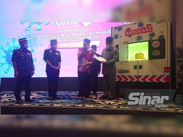 Mohd Ali (kanan) melihat buku yang dihasilkan Muhammad Din (dua dari kanan) ketika menyempurnakan program pelancaran buku berkenaan di Hotel Muzaffar, Ayer Keroh, Melaka pada Khamis.