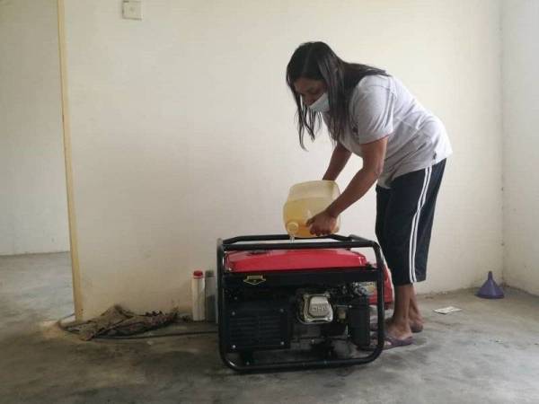Vijaya Letchumi menuang diesel untuk menghidupkan generator di rumahnya di flat Taman Desa Kempas, Johor Bahru pada Jumaat.