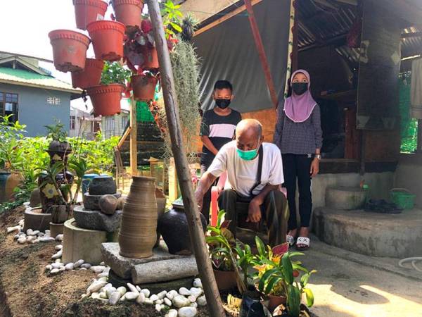 Ismail (tengah) bercucuk tanam di sekeliling bangsalnya.