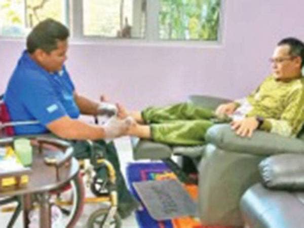 Fakruddin (kiri) mengurut salah seorang pelanggannya.