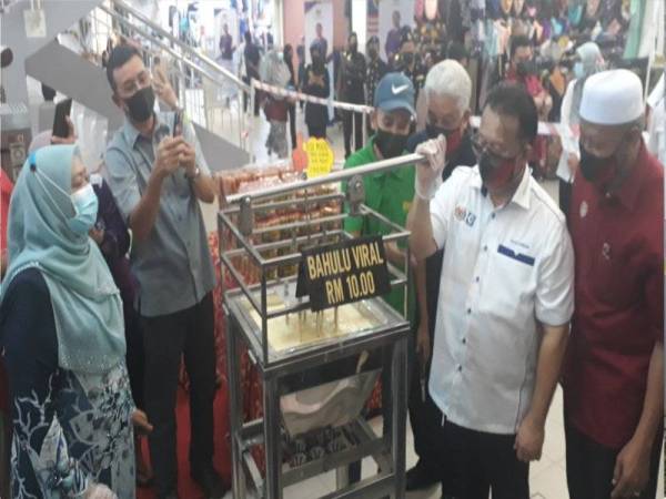 Alexander (dua kanan) cuba membuat kuih bahulu viral semasa melawat kedai-kedai di Kompels Pekan Rabu, Alor Setar pada Sabtu. Turut kelihatan Wan Romani (kanan).