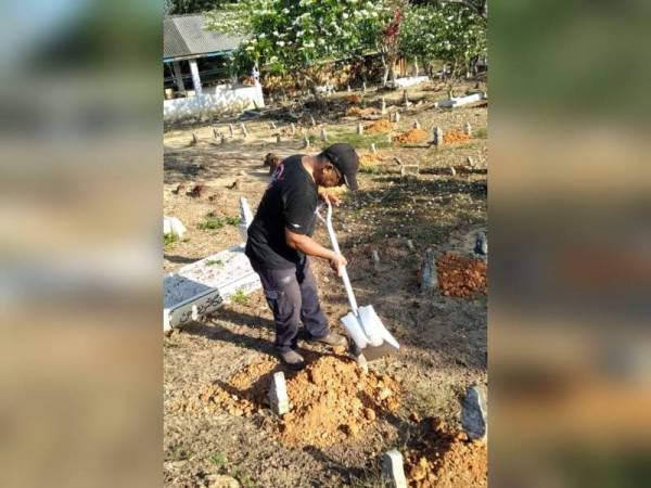 Salah seorang ahli sedang melakukan kerja-kerja menambak tanah di Tanah Perkuburan Bukit Tembakau, Serkam, Jasin.