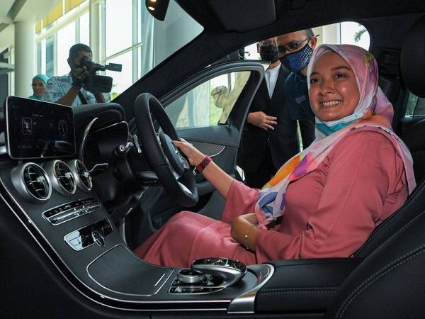 Ketua Eksekutif Perpadanan Tabung Pendidikan Nasional (PTPTN) Ahmad Dasuki Abdul Majid (berdiri, kanan) melihat pemenang tempat pertama Hadiah Cabutan Wow! SSPN-i Plus Tahunan 2020 Sonita Sudin (duduk) mencuba kereta Mercedes Benz C200 FL AMG Line yang dimenanginya pada majlis penyampaian hadiah tersebut hari ini.