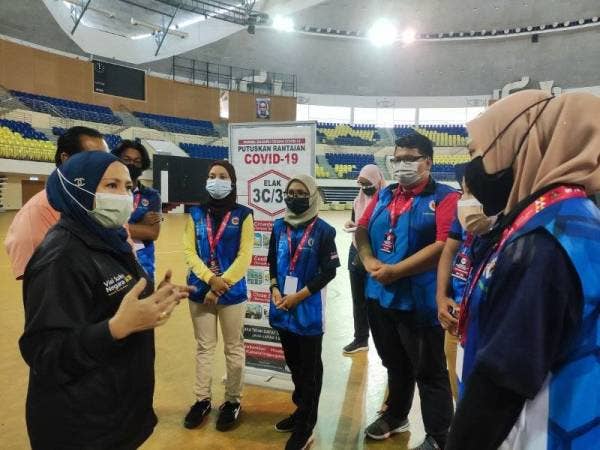 Dr Wasitah (kiri) berkata sesuatu kepada sukarelawan MyVac selepas melawat ke PPV Kuala Nerus di Stadium Tertutup Gong Badak di sini pada Ahad.