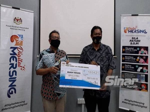 Abdul Latiff (kiri) menyerahkan sumbangan kepada penghulu-penghulu di Parlimen Mersing.