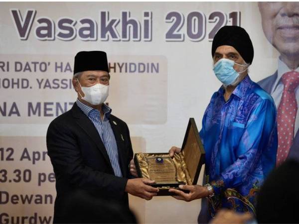 Muhyiddin (kiri) menerima cenderamata daripada Presiden Majlis Gurdwara Malaysia Sardar Jagir Singh (kanan) ketika hadir pada majlis minum petang sempena perayaan Vaisakhi di Gurdwara Sahib Lorong Utara, Petaling Jaya pada Isnin.